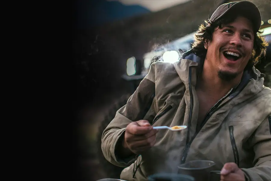 Man eating from a food pouch by headlamp