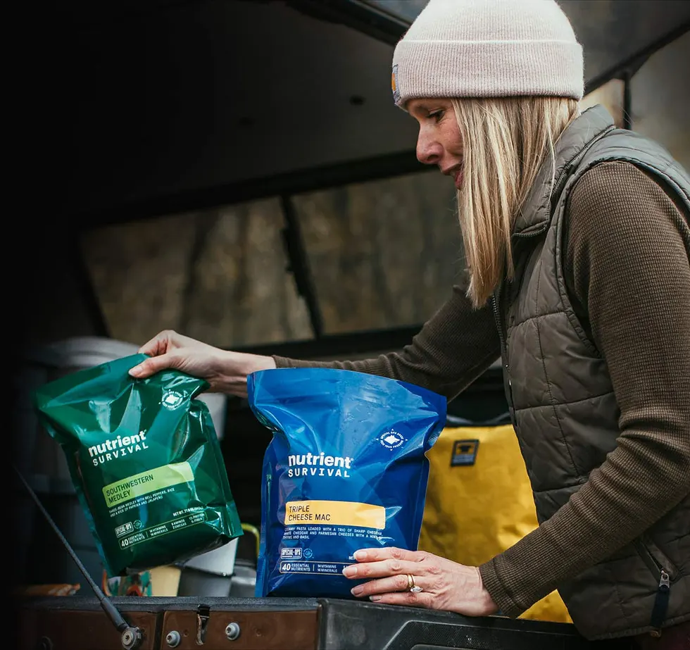 Woman in a knit hat unpacking Nutrient Survival food pouches from the back of a truck